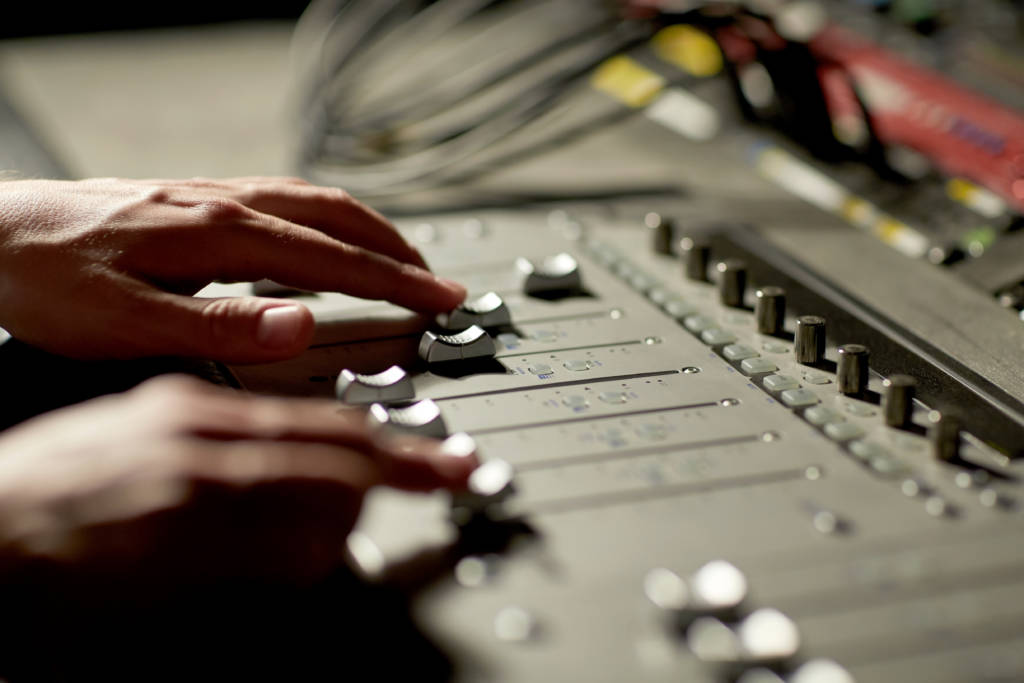hands on mixing console in music recording studio