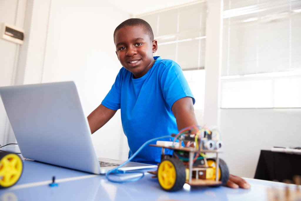 Portrait Of Male Student Building And Programing Robot Vehicle In School Computer Coding Class