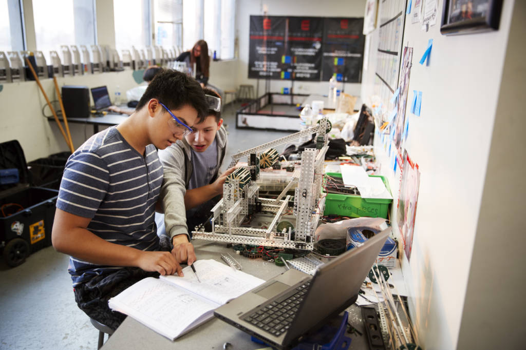 Two Male College Students With Laptop Building Machine In Science Robotics Or Engineering Class
