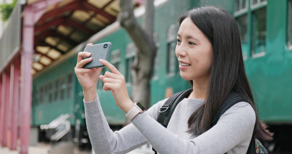 Woman traveler using smart phone for taking photo and video