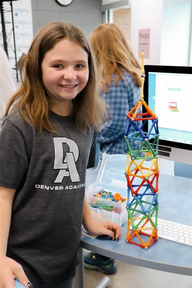 young-girl-standing-next-to-a-colorful-tower-she-built-out-of-multicolored-rods.