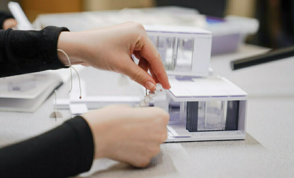 close up shot of a students hands building something out of white and clear plastic components in a stem smartlab setting