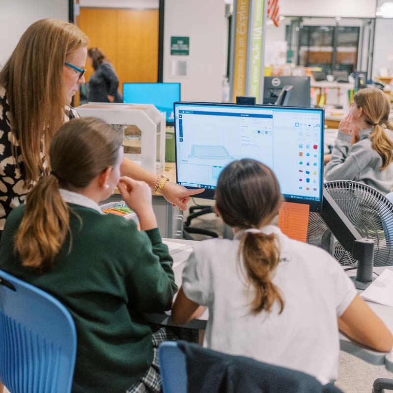 Facilitator teacher engaging with students in the SmartLab on CAD project.