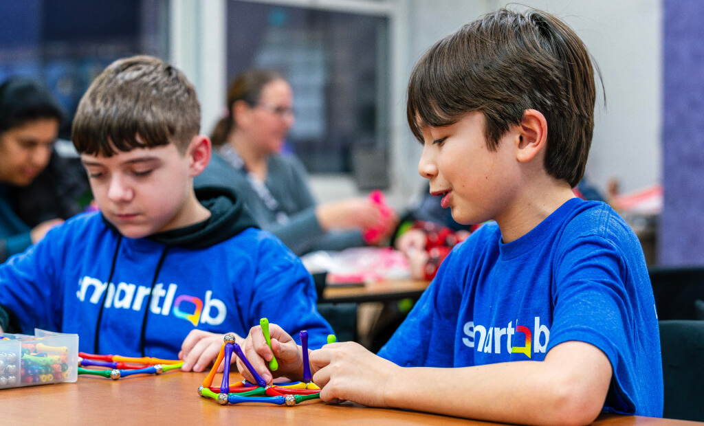 Two young boys collaborate on a project, focused and engaged in their work together.