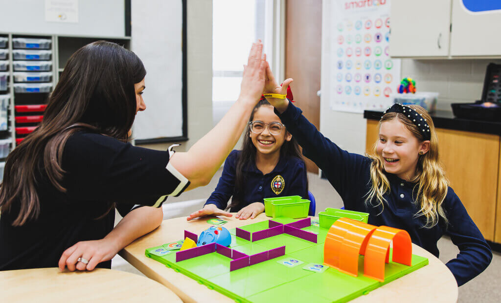 Kids and teacher at a table high-fiving