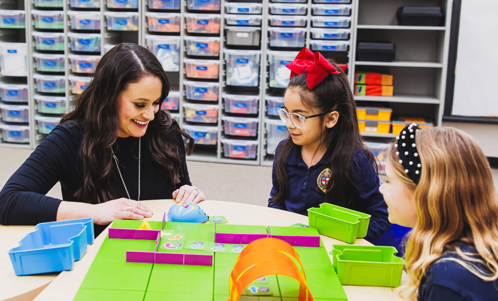 a school-aged girl and her teacher sit at a classroom table together in a smartlab setting